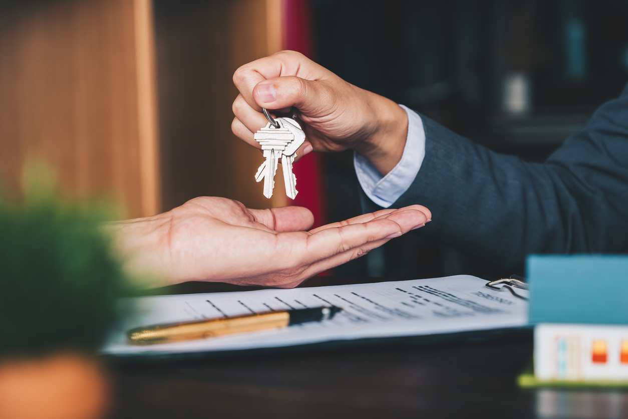 real estate agent handing the house key to the new home owner -Destination Properties